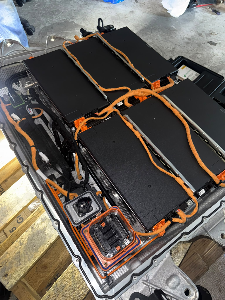 Opened electric vehicle battery pack with orange high-voltage cables